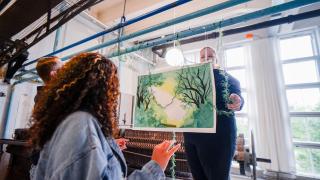 Kolme nuorta ripustaa teosta galleriaan.